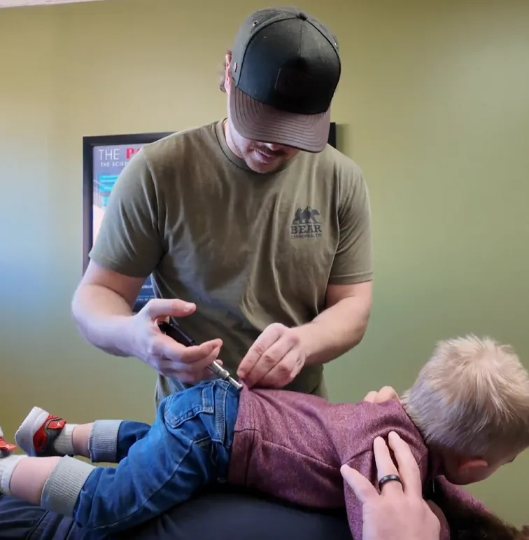 Chiropractor using an activator on a child's back
