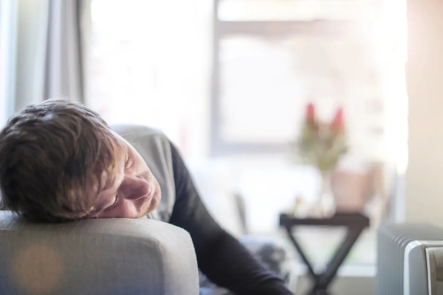Tired man resting his head on a couch arm