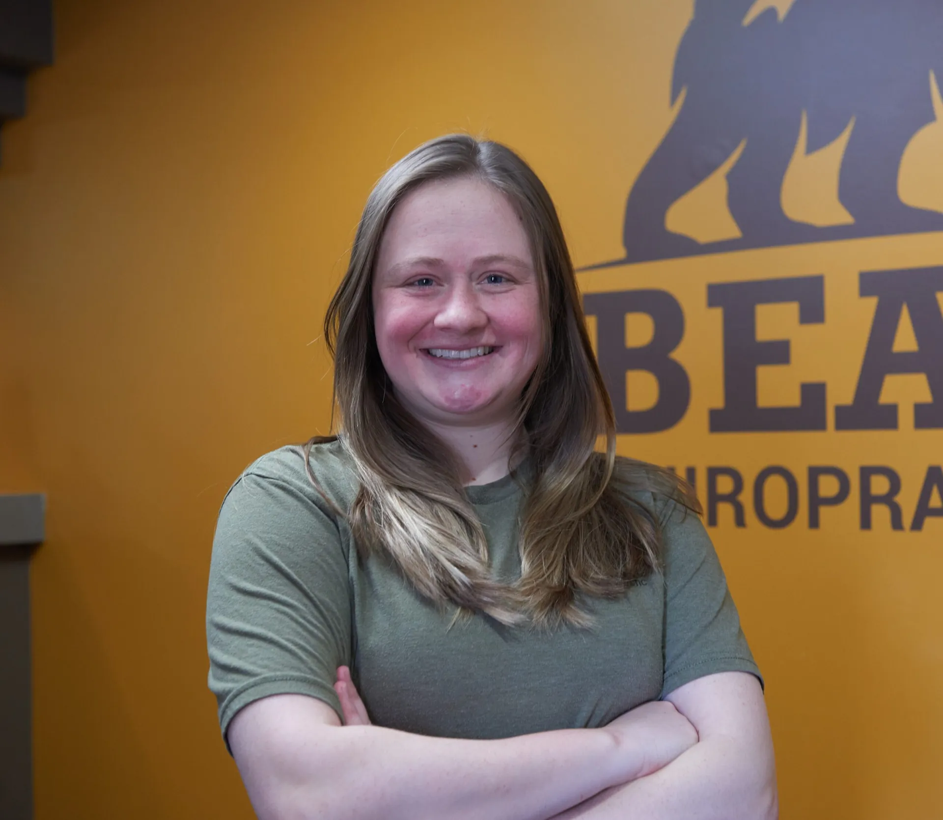 Amber Alferink, Massage Therapist, smiling in front of the Bear logo