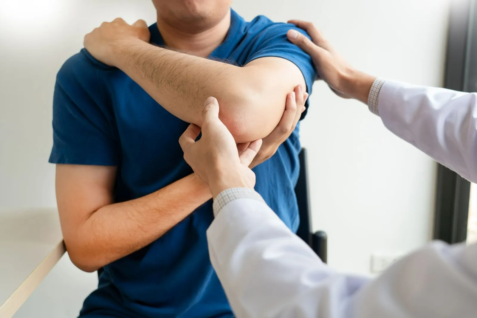 Therapist moving a patient's bent elbow and shoulder
