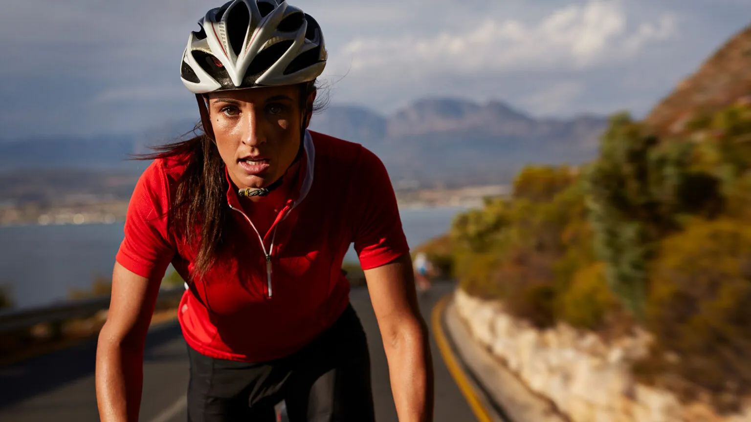 Tired woman cyclist in a helmet on a mountain road
