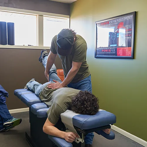Chiropractor adjusting a patient lying face down on a table