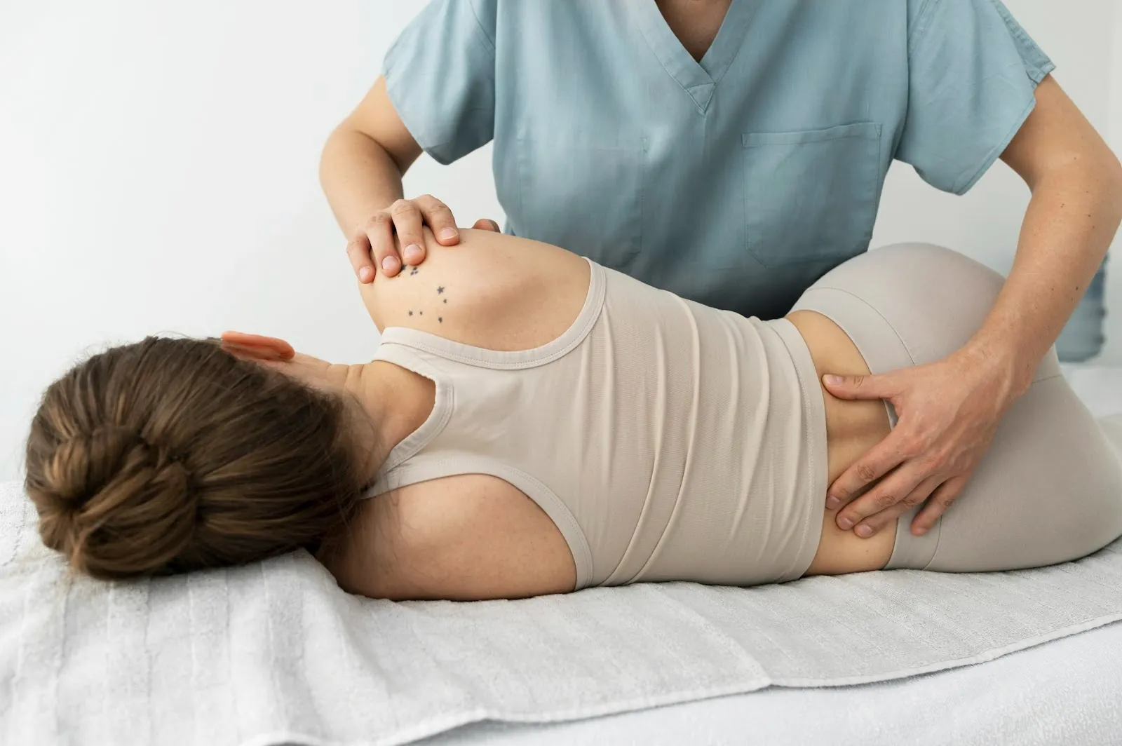 Practitioner treating a woman's lower back and hip on a table