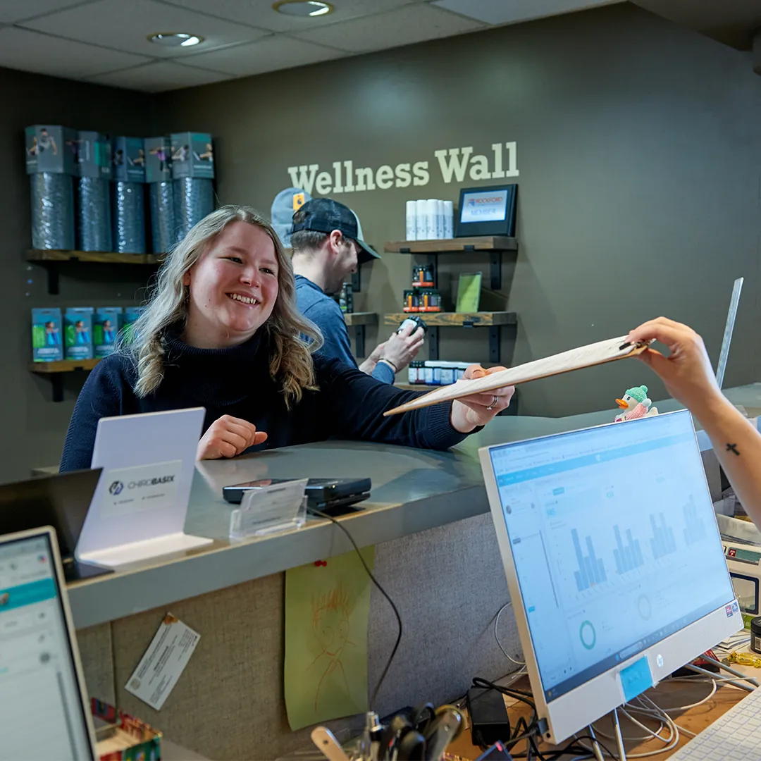 Front desk staff member smiling and handing a form to a patient