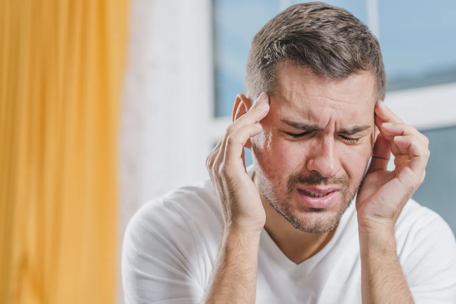 Man pressing his temples with a pained expression