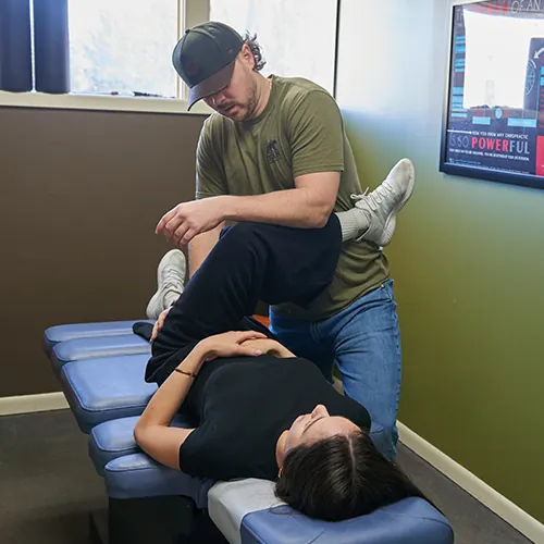 Chiropractor bending a patient's leg during a hip assessment