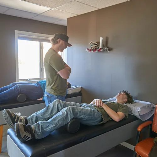 Patient lying on a roller table while the chiropractor stands nearby