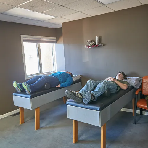 Two patients lying on roller tables in a therapy room