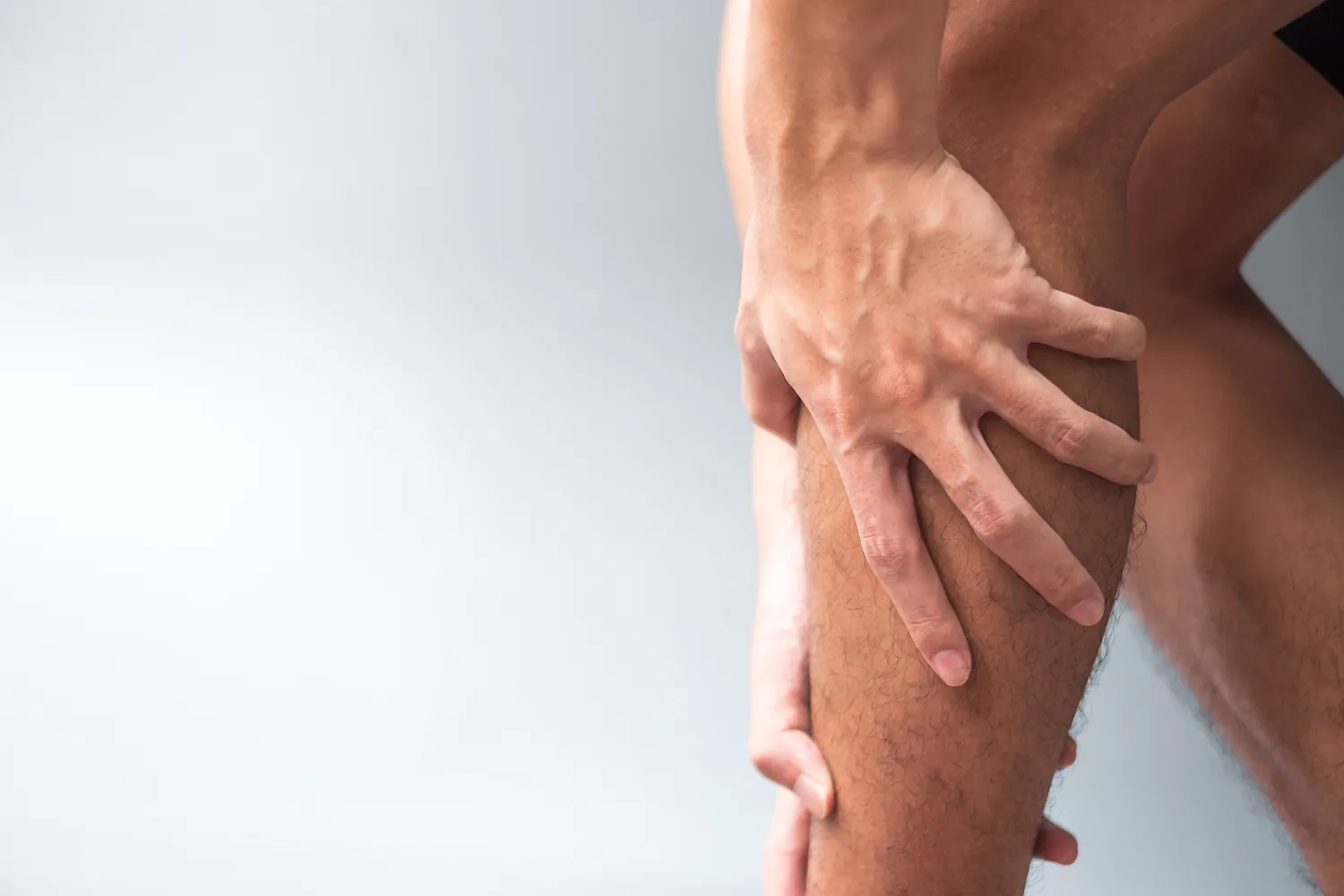 Hand gripping the calf of a bare leg