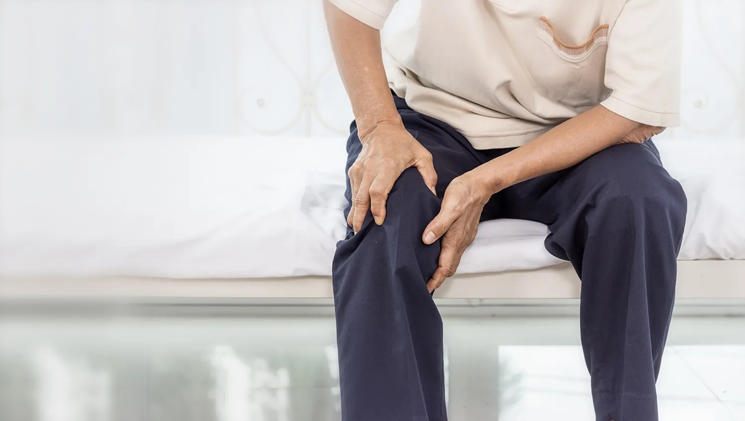 Seated man gripping his knee with both hands