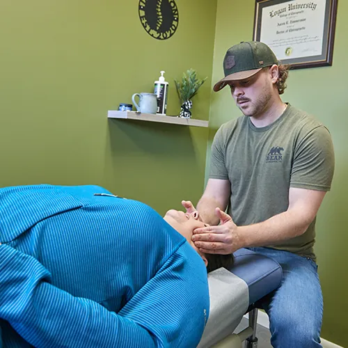 Chiropractor examining a patient's neck as she lies on a table