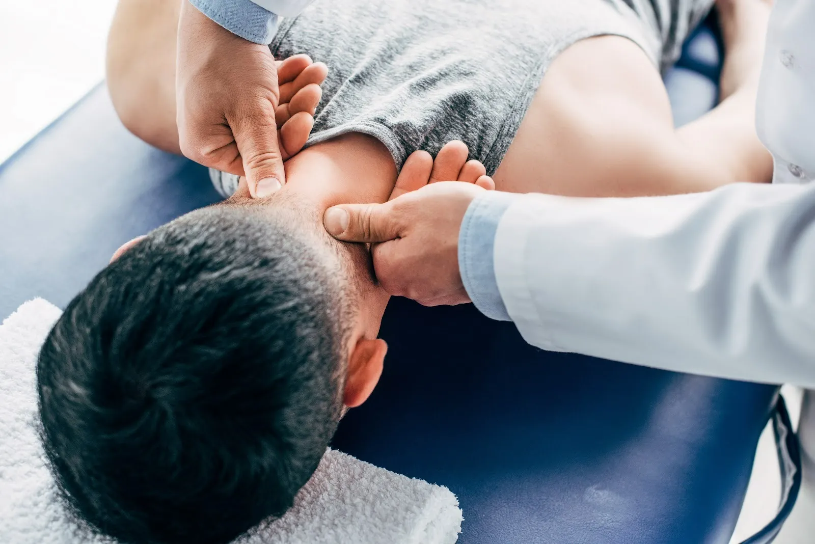 Chiropractor's hands treating a patient's neck on a table