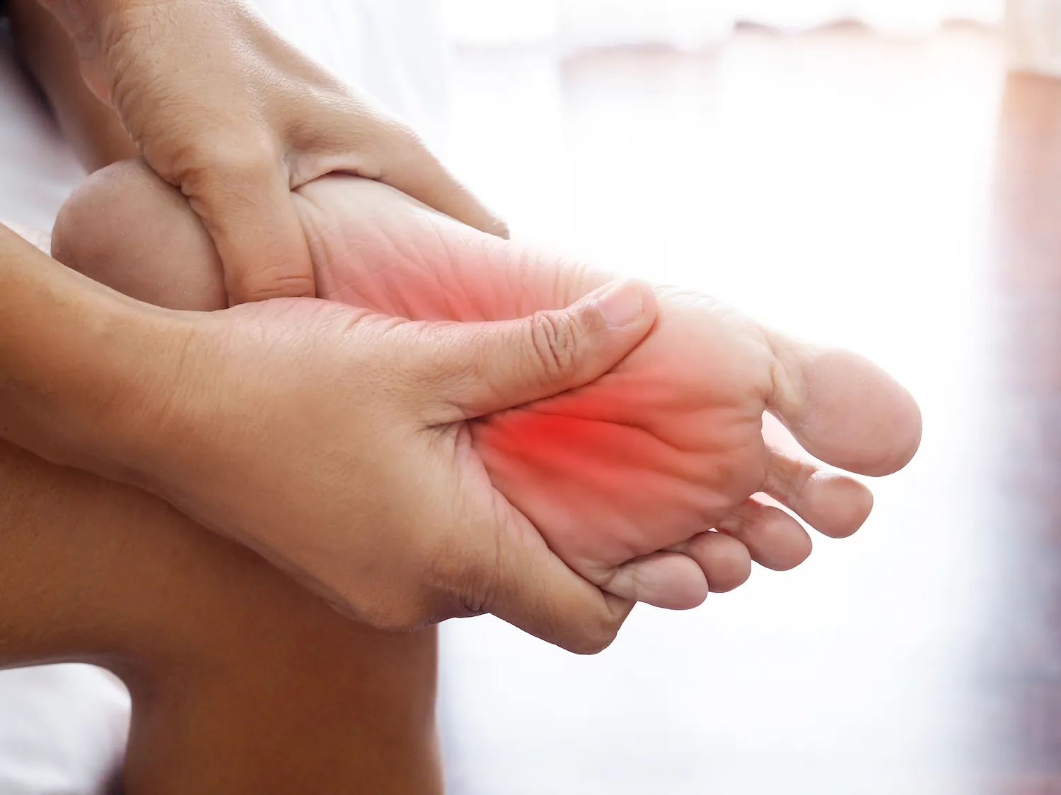 Hands holding a foot with the sole highlighted red