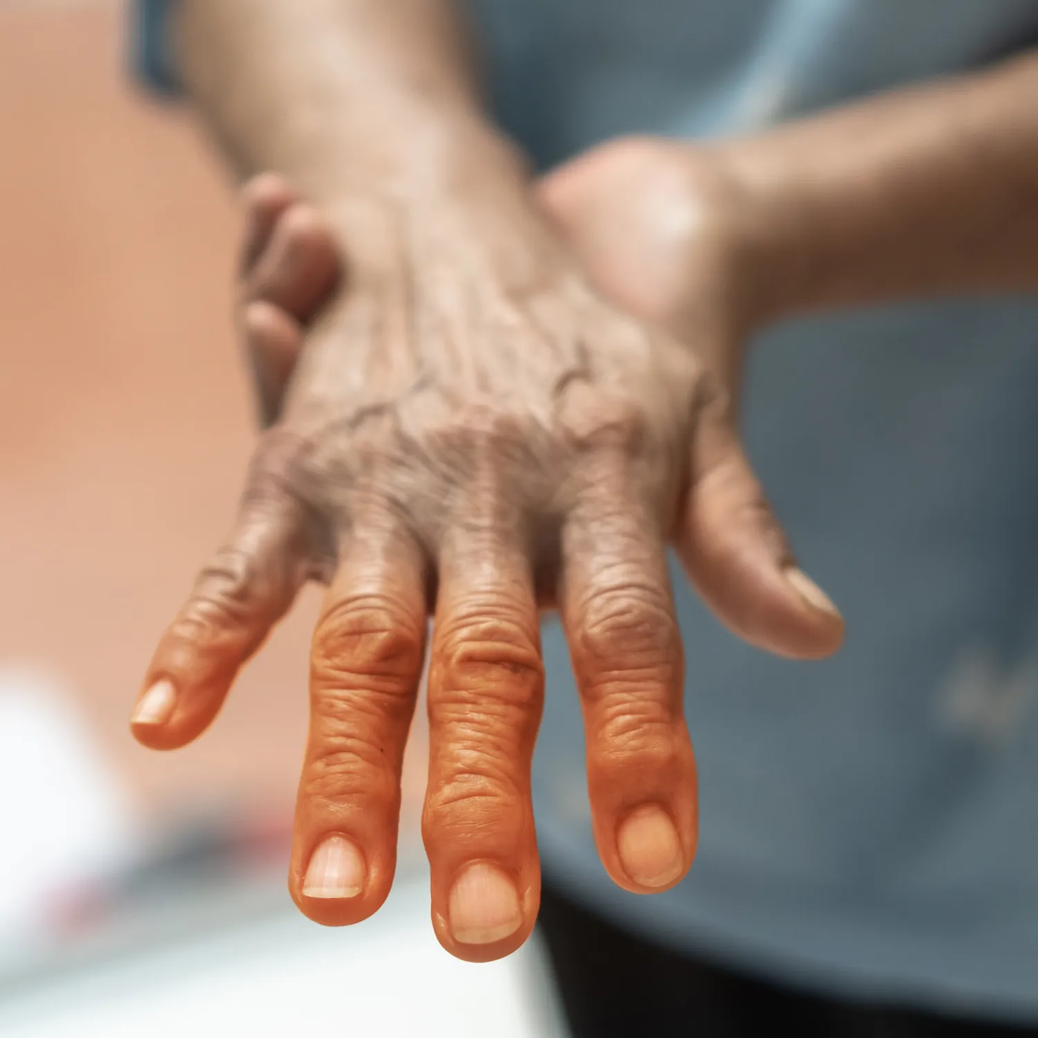 Older hand with fingertips highlighted orange