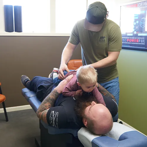 Dr. Aaron Zimmerman adjusting a toddler lying on a parent's chest