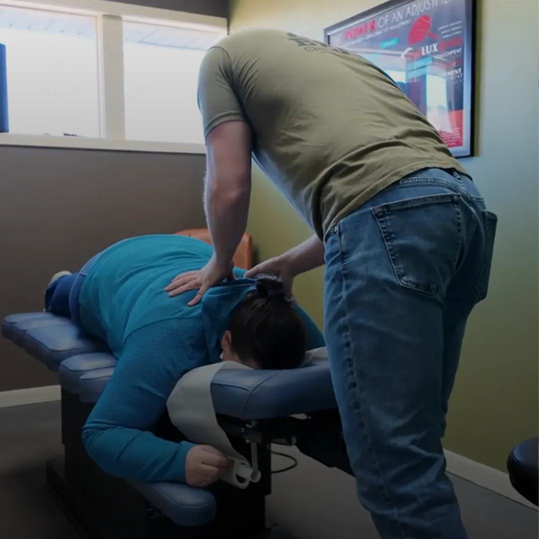 Chiropractor adjusting the upper back of a patient on a table