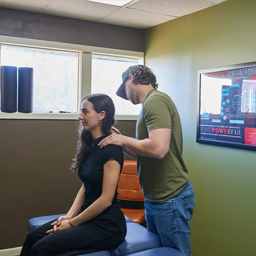 Dr. Aaron Zimmerman checking a seated woman's shoulders and posture