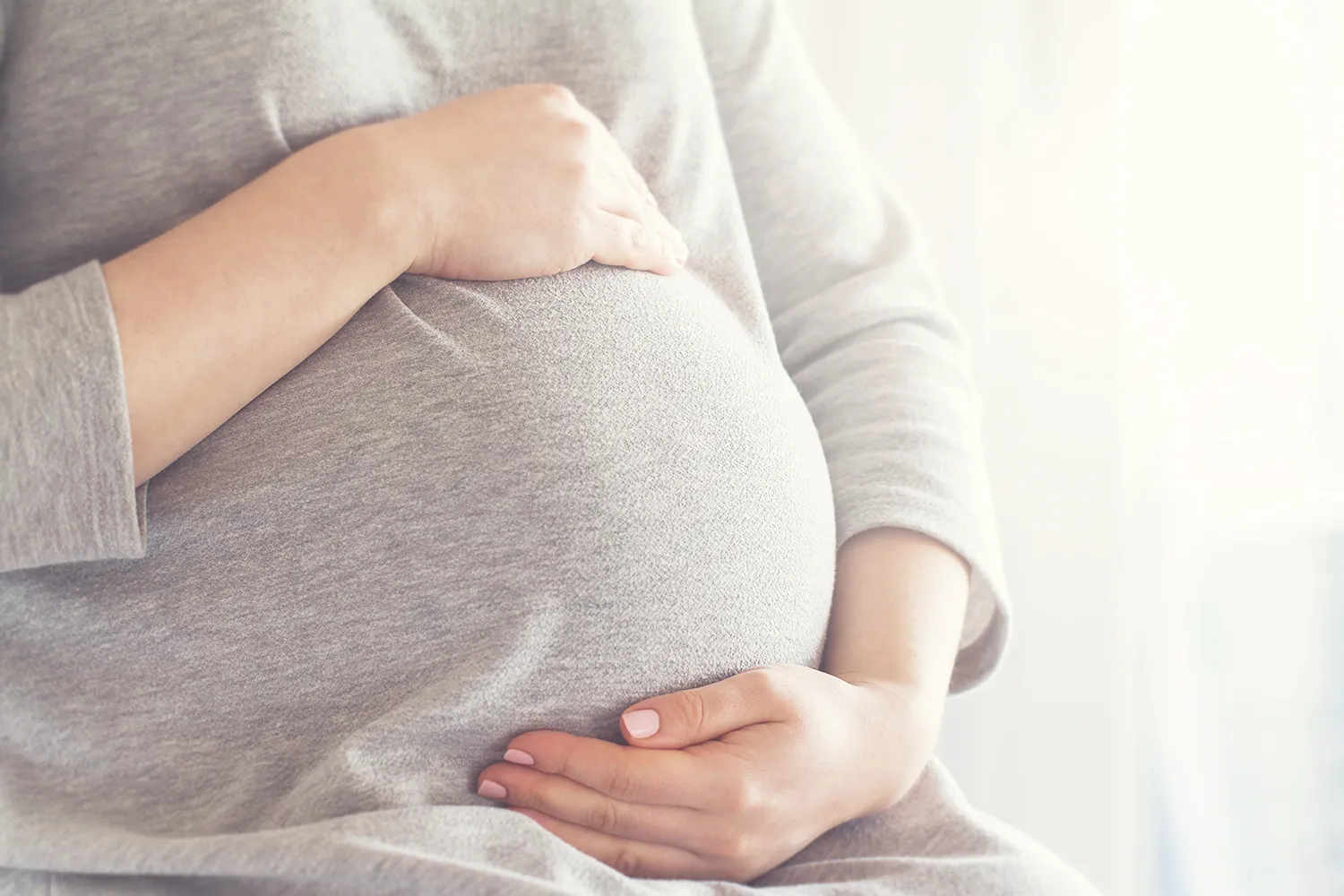 Pregnant woman with both hands resting on her belly