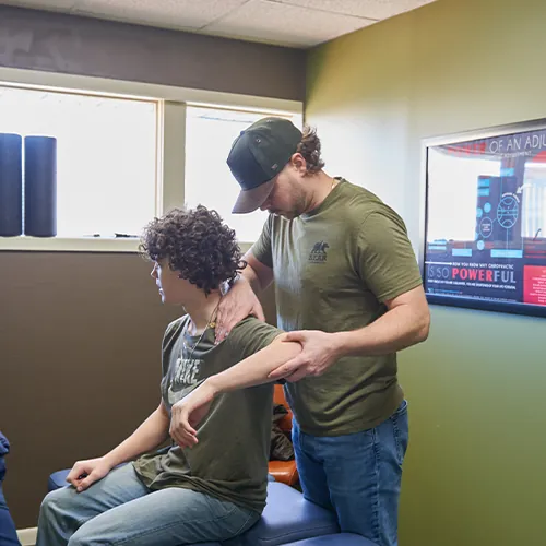 Dr. Aaron Zimmerman guiding a seated patient's arm and shoulder