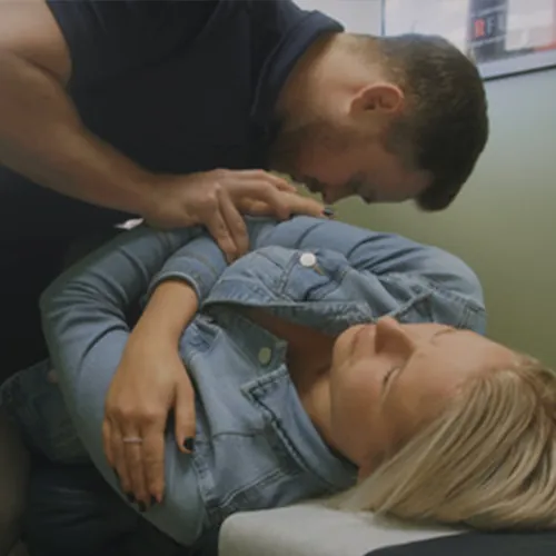 Chiropractor adjusting the shoulder of a woman lying on her side