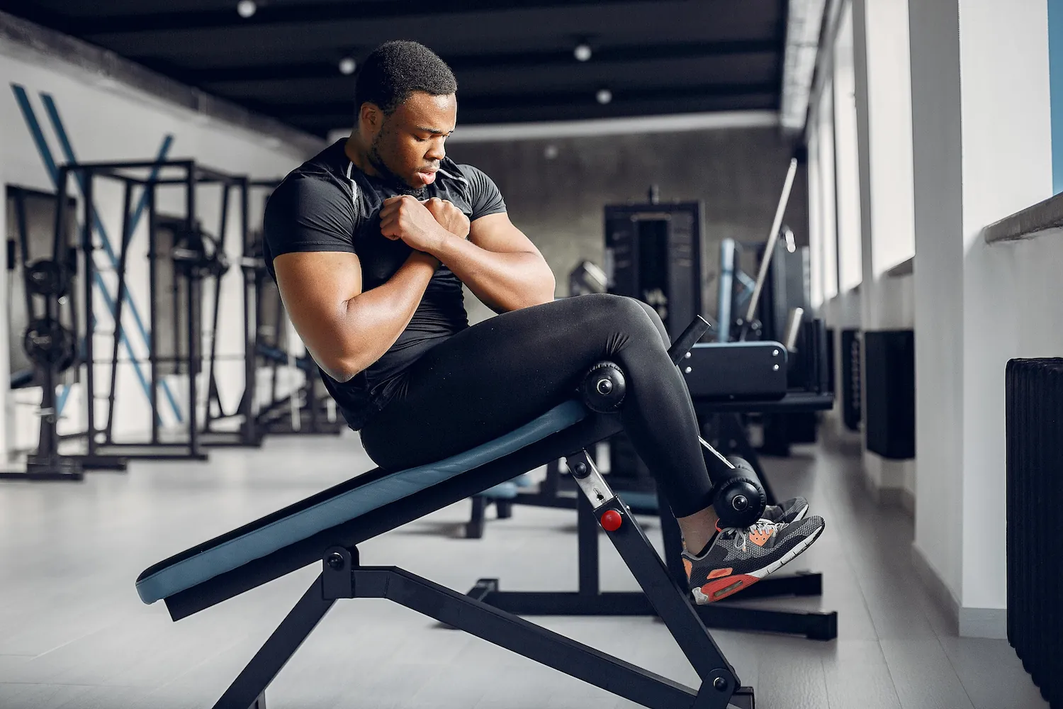 Athletic man sitting on a gym bench with arms crossed