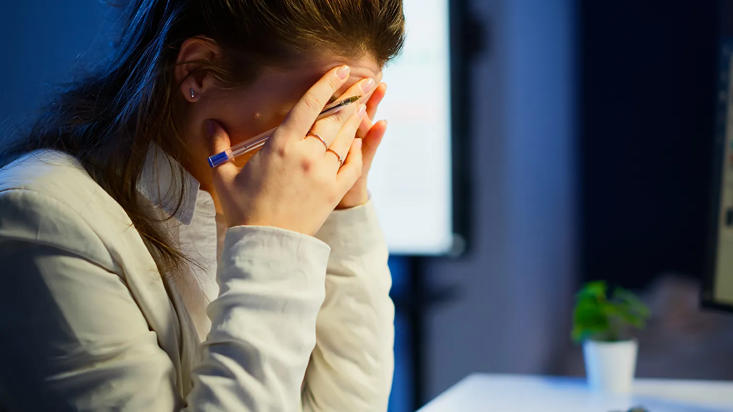 Woman covering her face with her hands at a desk