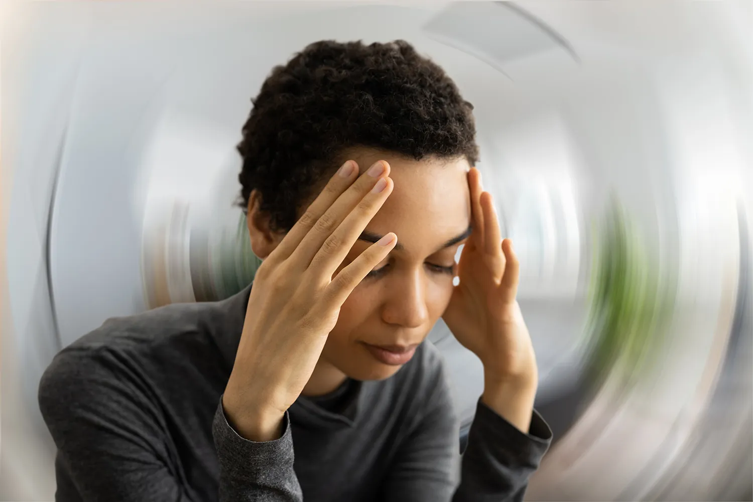 Woman holding her head with a spinning blur behind her