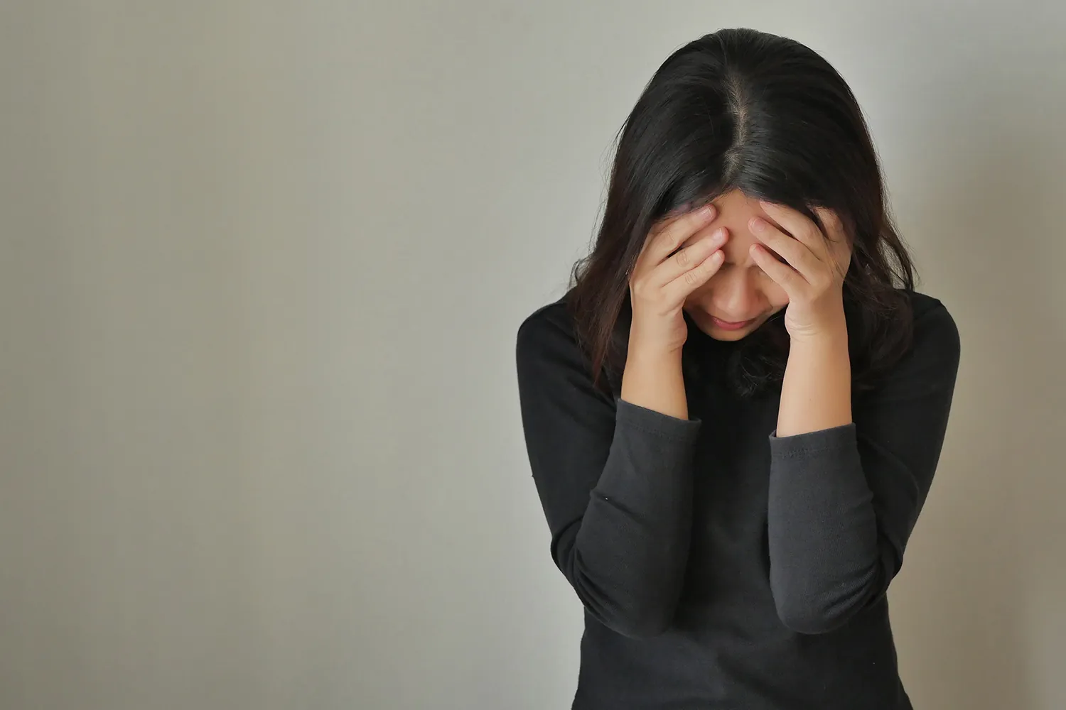 Woman standing with both hands on her head