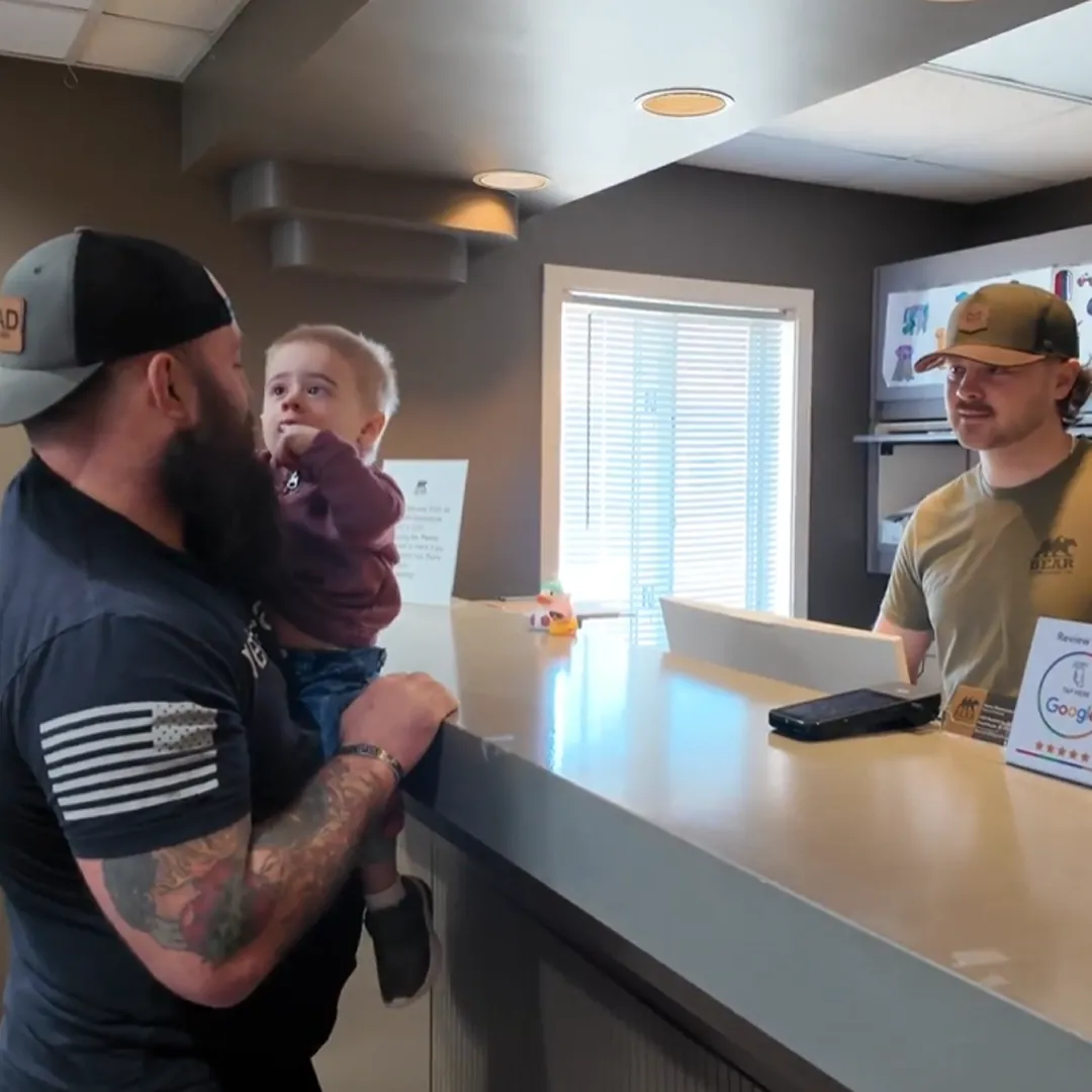 Father holding a toddler at the Bear Chiropractic front desk