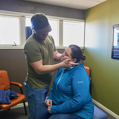 Chiropractor examining a seated patient's neck and jaw