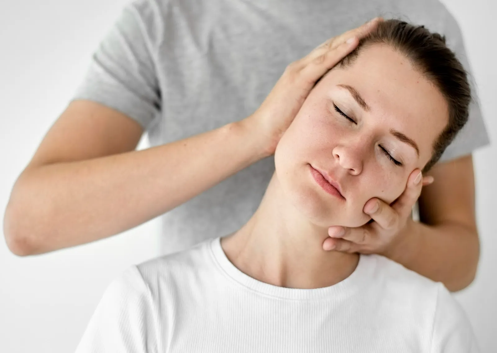Chiropractor's hands gently supporting a woman's head and jaw