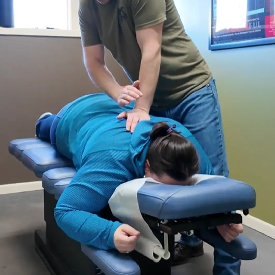 Chiropractor adjusting a patient's upper back on a table